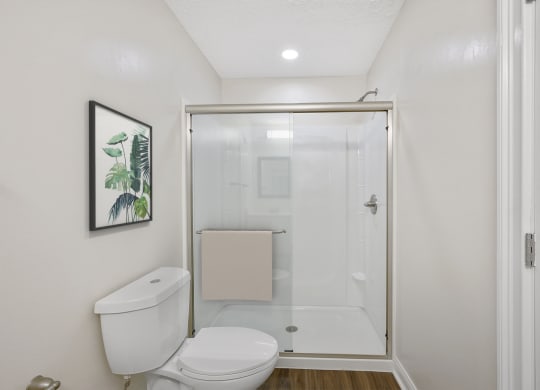 a bathroom with a toilet and a shower with a glass door at Harpers Point Apartments, Cincinnati, OH