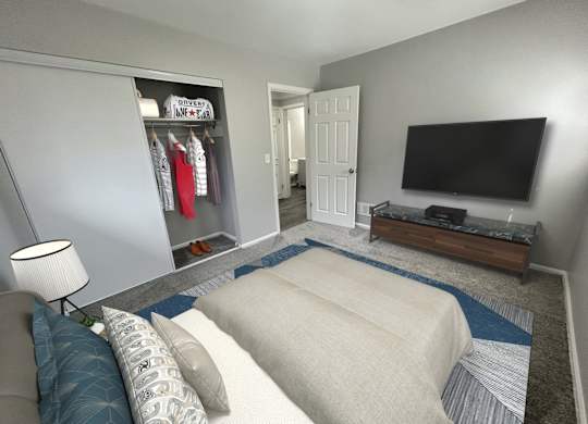 A living room with a couch, a television, and a clothing rack.