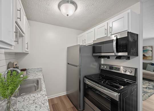 A kitchen with a sink, stove, and microwave.