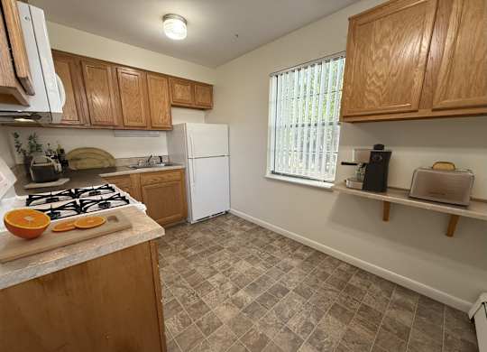 A kitchen with a white refrigerator and wooden cabinets.