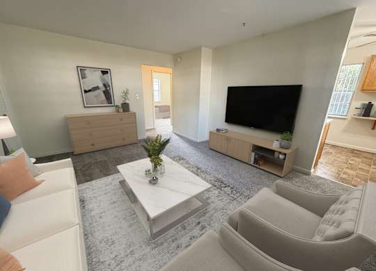 A living room with a grey carpet and a white coffee table.