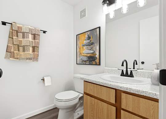 A bathroom with a toilet, sink, and a painting on the wall.