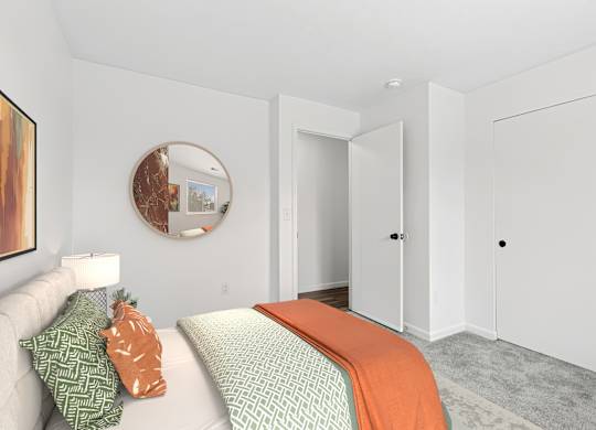 A bedroom with a bed, a couch, and a painting on the wall.