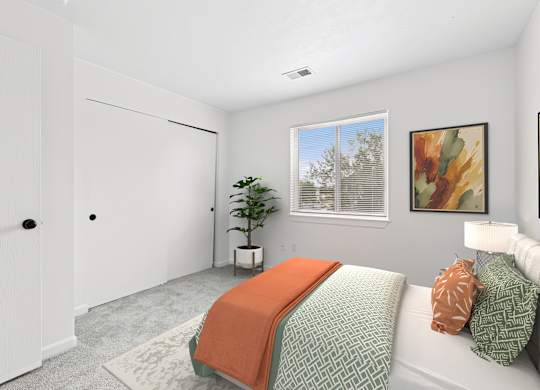 A bedroom with a bed, pillows, and a window.