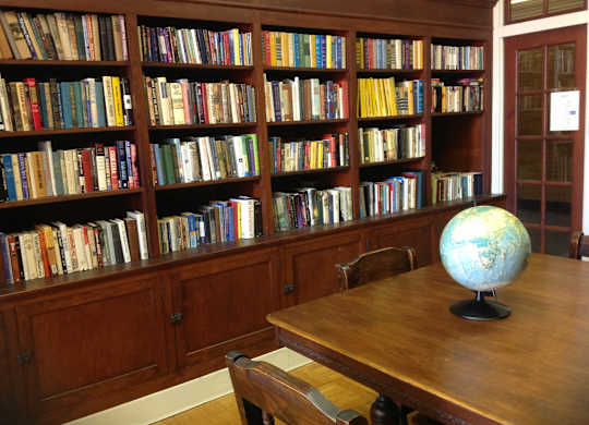 A room with a bookshelf filled with books and a globe on the table.