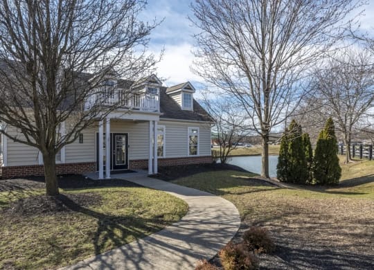 a white house with a driveway and a lake in the background at Traditions at Slate Ridge, Reynoldsburg, OH 43068