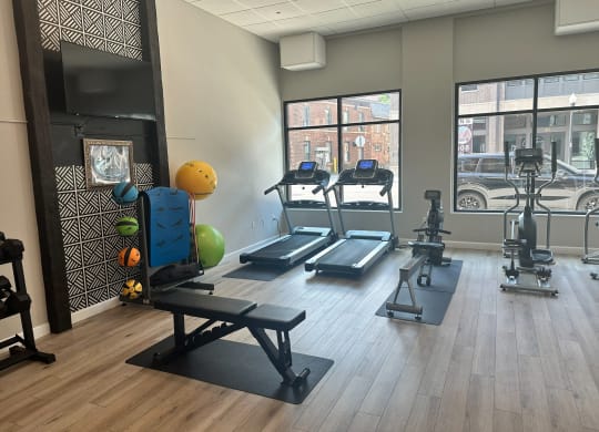 a gym with treadmills and weights on a wooden floor at Adelphi Quarter, Columbus, 43203