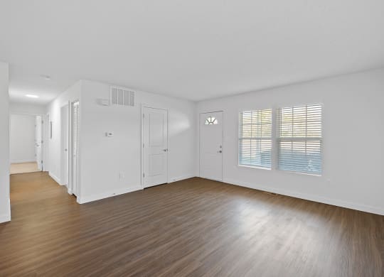 an empty living room with wood floors and white walls