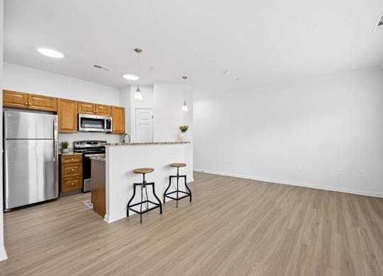 A kitchen with a refrigerator, microwave, and bar stools.