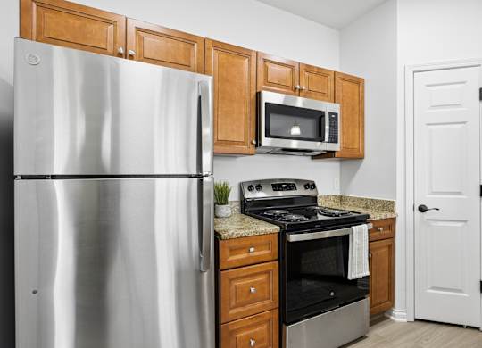A kitchen with a refrigerator, microwave, oven, and cabinets.