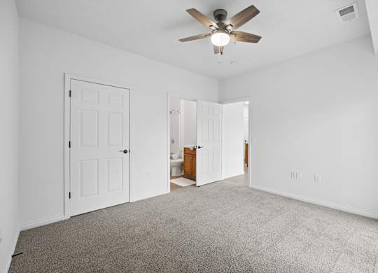 A room with a ceiling fan and carpeted floor.