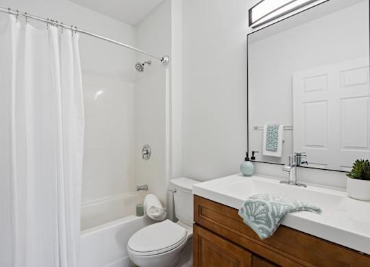 A white bathroom with a toilet, sink, and shower.
