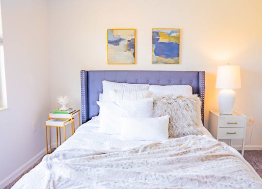a bedroom with a bed with white sheets and pillows and two nightstands
