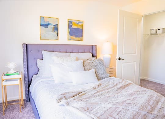 a bedroom with a bed and two paintings on the wall