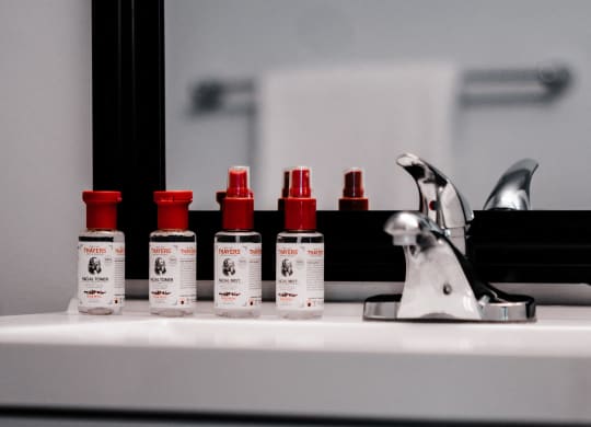 four bottles of cosmetics sitting on top of a bathroom sink