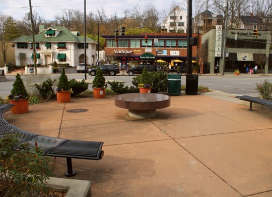a park with benches and a stone table on a city street