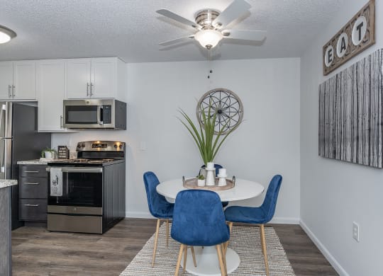 an open kitchen and dining area with a table and chairs and a ceiling fan