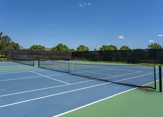 a tennis court on a sunny day with trees in the background at Bishops Gate, Ohio
