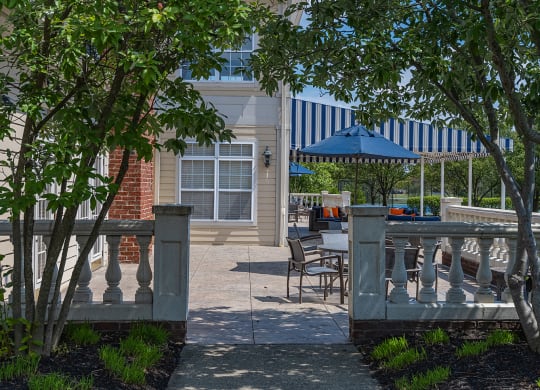 a patio with tables and chairs and a blue umbrella in front of a building at Bishops Gate, Cincinnati, OH
