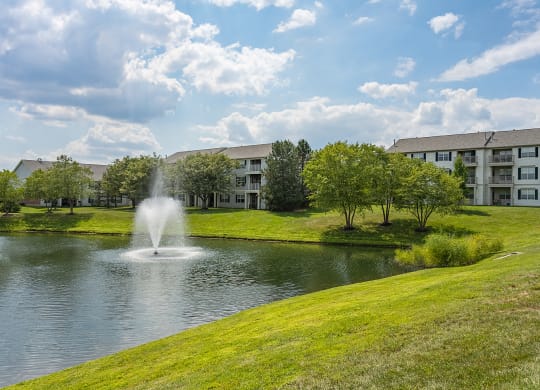 a fountain in the pond with an apartment building in the background at Bishops Gate, Ohio