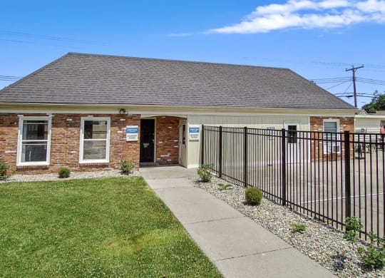 a small brick building with a black fence in front of it
