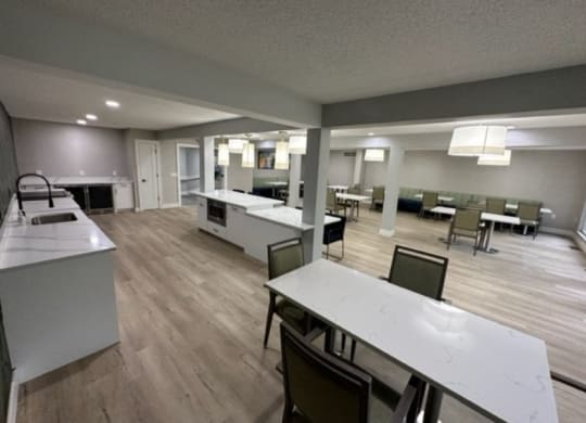 a large room with tables and chairs and a kitchen