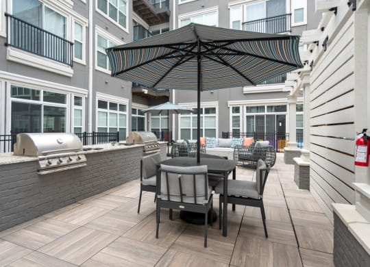 a patio with a grill and umbrella at the bradley braddock road station apartments