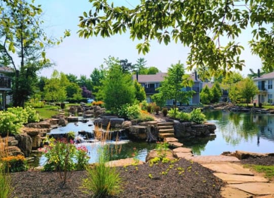 a pond with rocks and trees in the background at Harpers Point Apartments, Cincinnati, OH