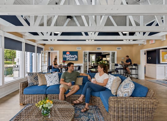 A man and woman are sitting on a couch in a room with a sign that says "Hanover's.".