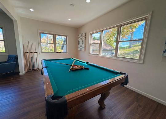 A pool table in a room with a view of the backyard.
