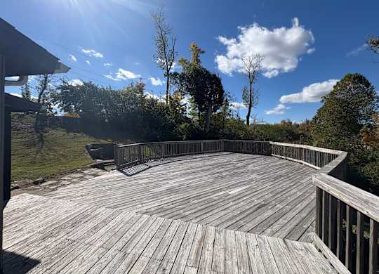 A wooden deck overlooks a grassy area with trees.
