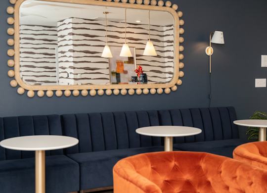 a blue couch and tables in a room with a mirror on the wall at Monmouth Row Apartments, Newport, KY