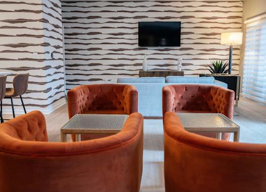 a seating area with orange chairs and a television at Monmouth Row Apartments, Newport, KY