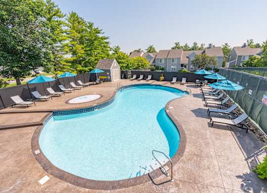 A large outdoor swimming pool surrounded by lounge chairs and umbrellas.