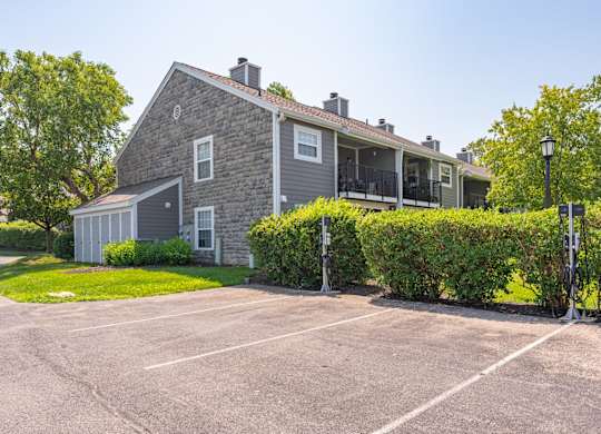A grey house with a parking lot in front.