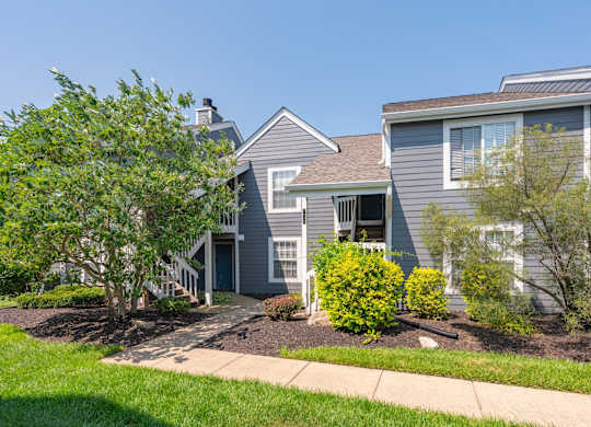 A grey house with a tree in front.