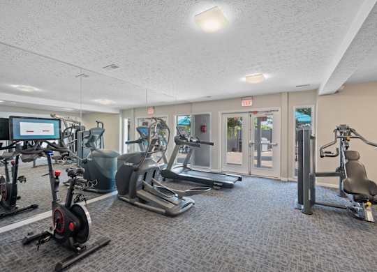 A gym with a variety of equipment including treadmills, stationary bikes, and weight machines.