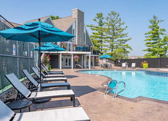A pool area with a row of lounge chairs and umbrellas.