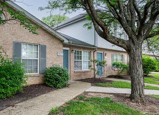 A house with a blue door and a tree in front.