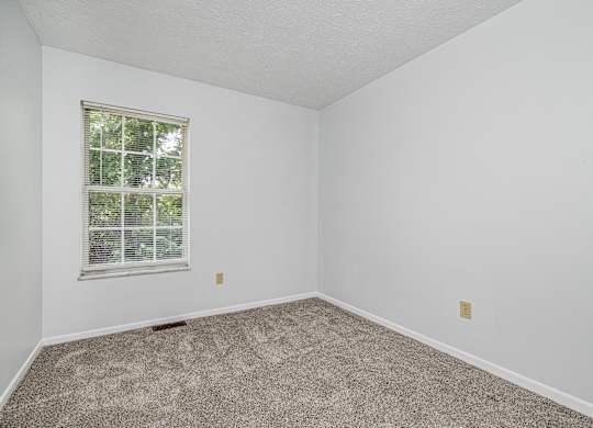 A room with a carpeted floor and a window.