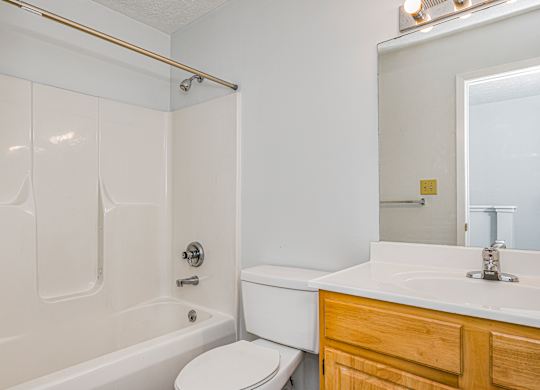A white bathroom with a toilet, sink, and bathtub.