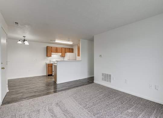 an empty living room and kitchen with white walls and wood flooring