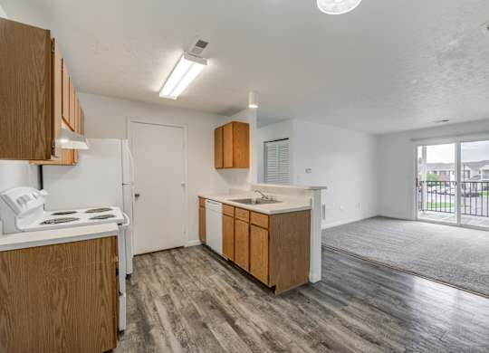 an empty kitchen and living room with a door to a balcony