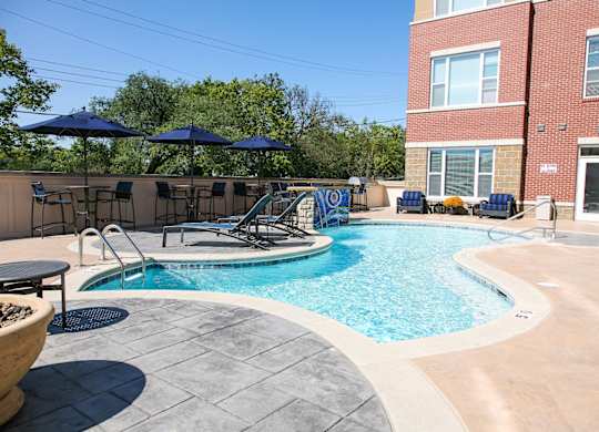 A pool with a table and chairs and umbrellas.