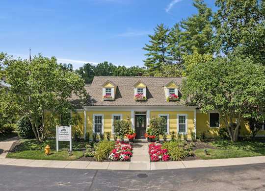 A yellow house with a white sign in front.