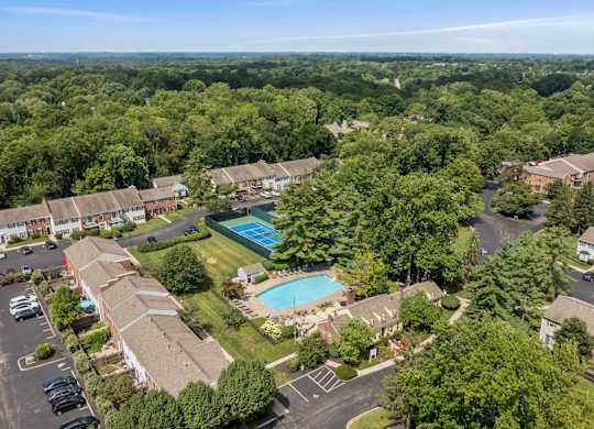 An aerial view of a residential complex with a swimming pool surrounded by trees.