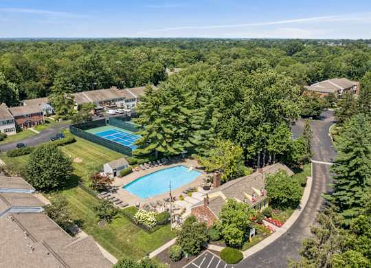 A bird's eye view of a residential area with a swimming pool and a winding road.