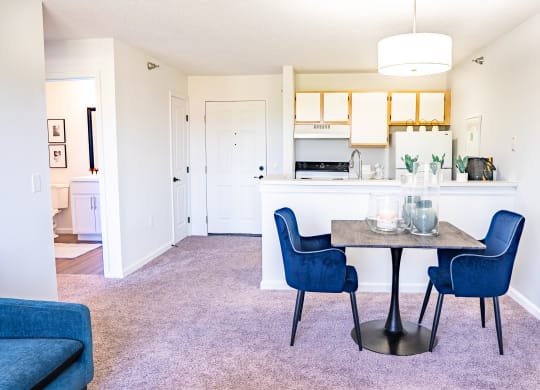 a dining area with a table and chairs and a kitchen in the background