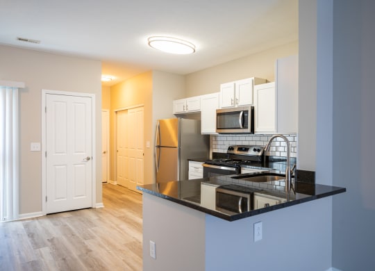 a kitchen with a black counter top and a stainless steel refrigerator at Traditions at Slate Ridge, Reynoldsburg, OH 43068