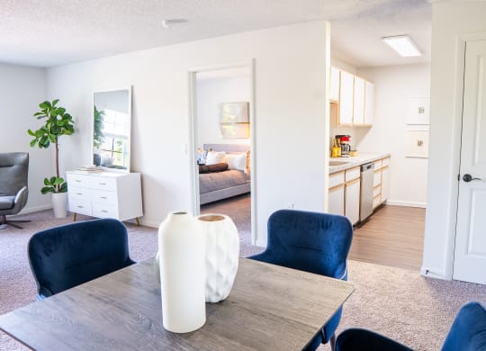 a living room with a dining room table and chairs and a kitchen in the background